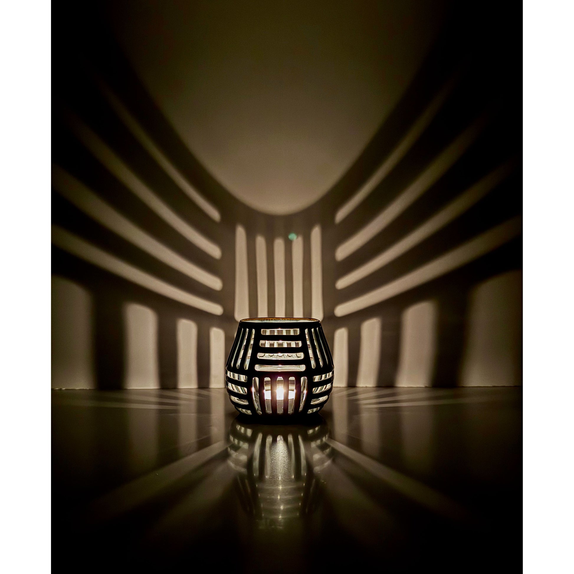 Decorative ceramic lantern with grid pattern casting shadows on a wall