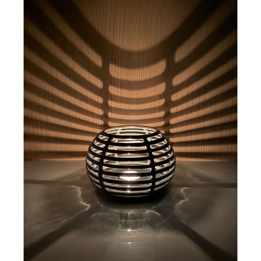Decorative ceramic candle holder with grid pattern casting shadows on a wall