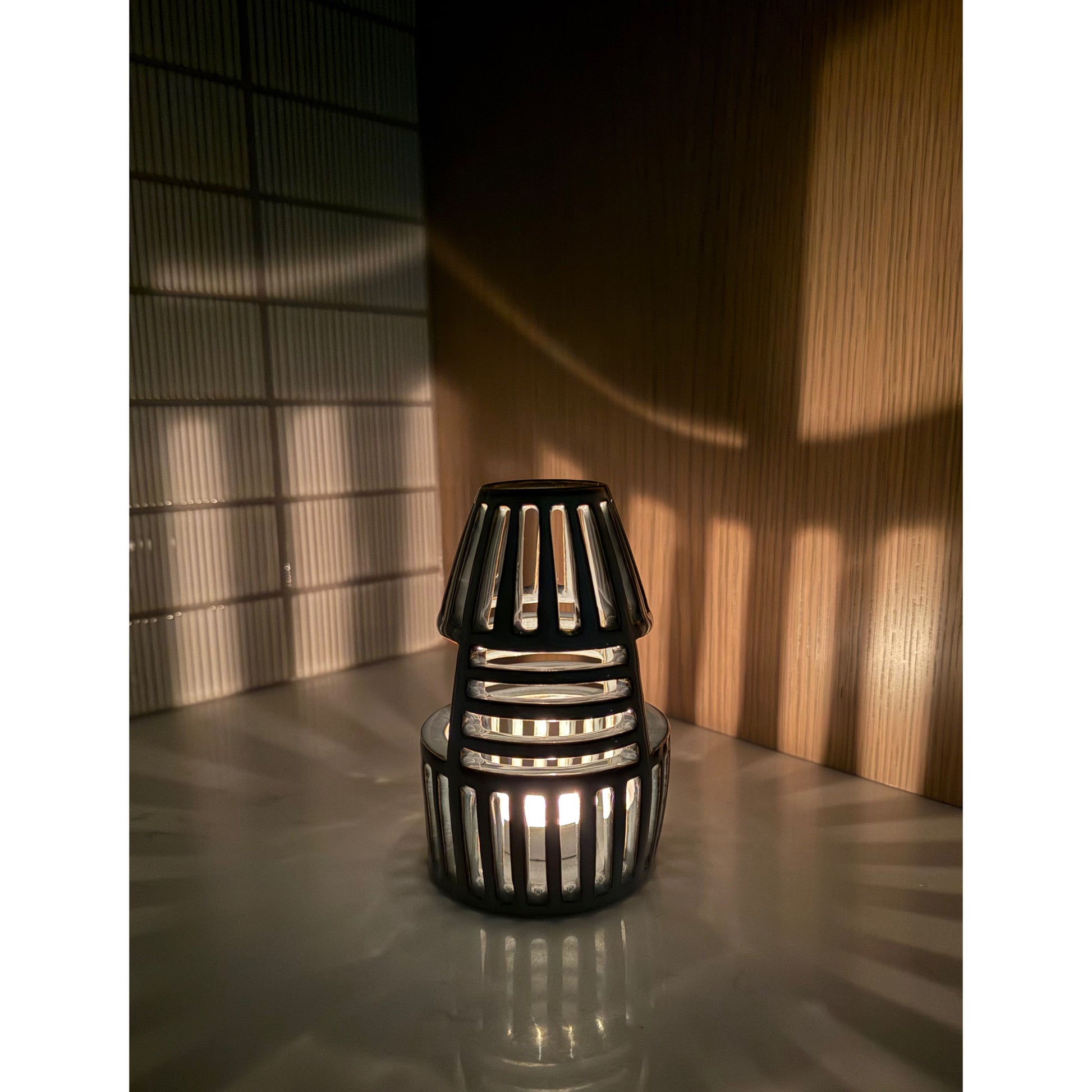 Decorative lantern with a warm glow on a reflective surface.