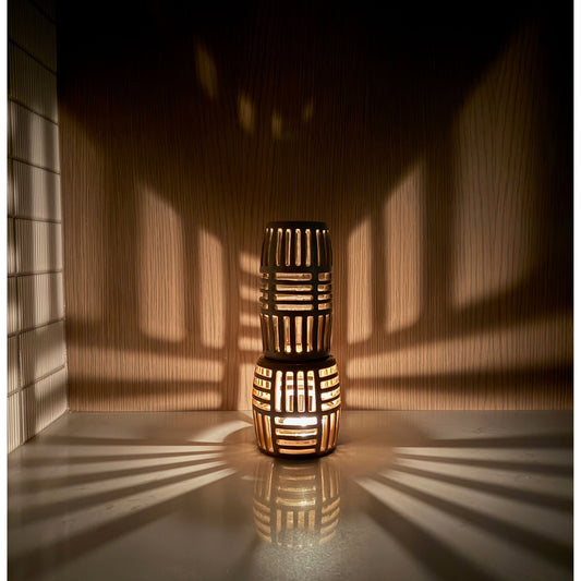 Two stacked woven lanterns casting shadows on a wall.